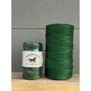 Two green spools of thread with a label on a wooden surface.