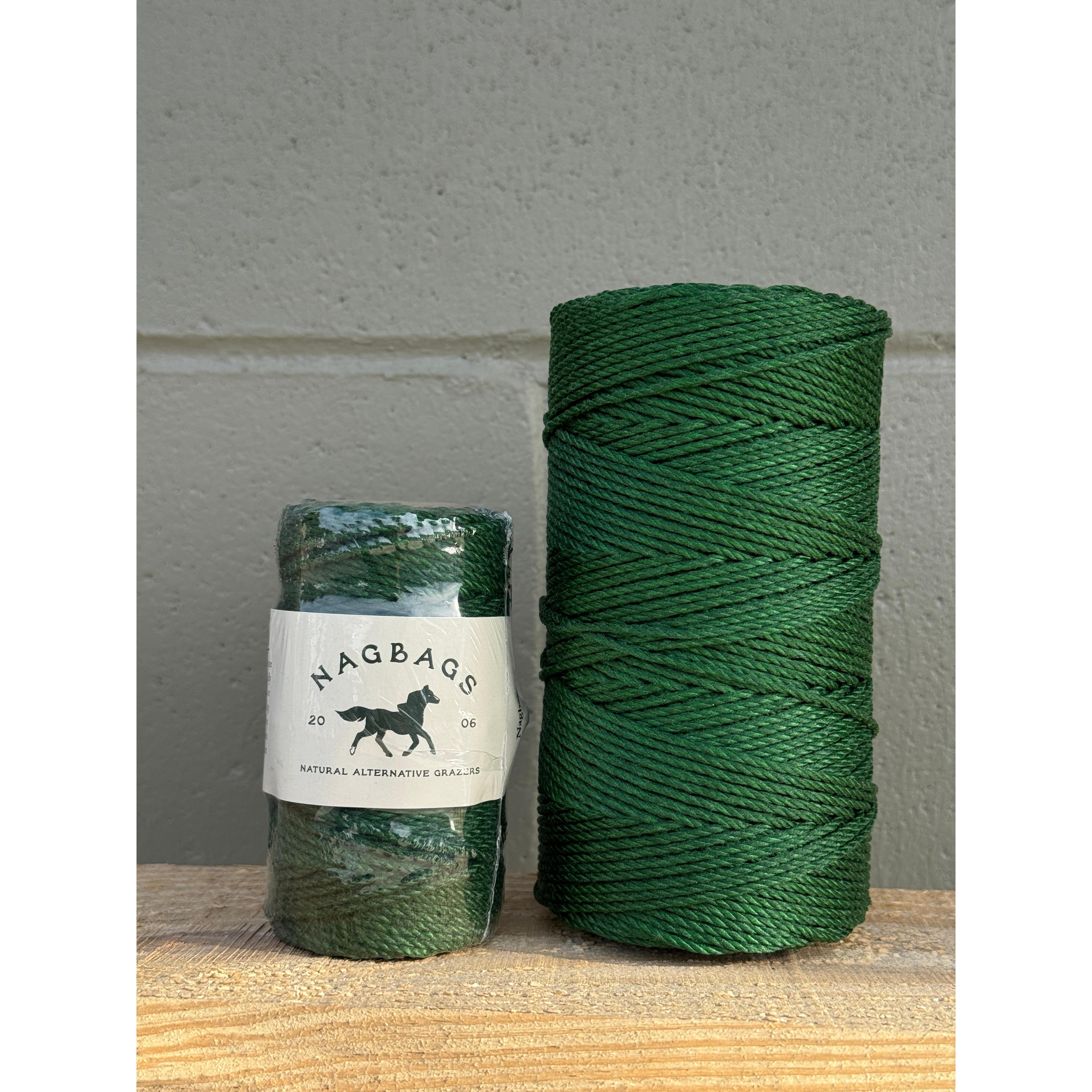 Two green spools of thread with a label on a wooden surface.