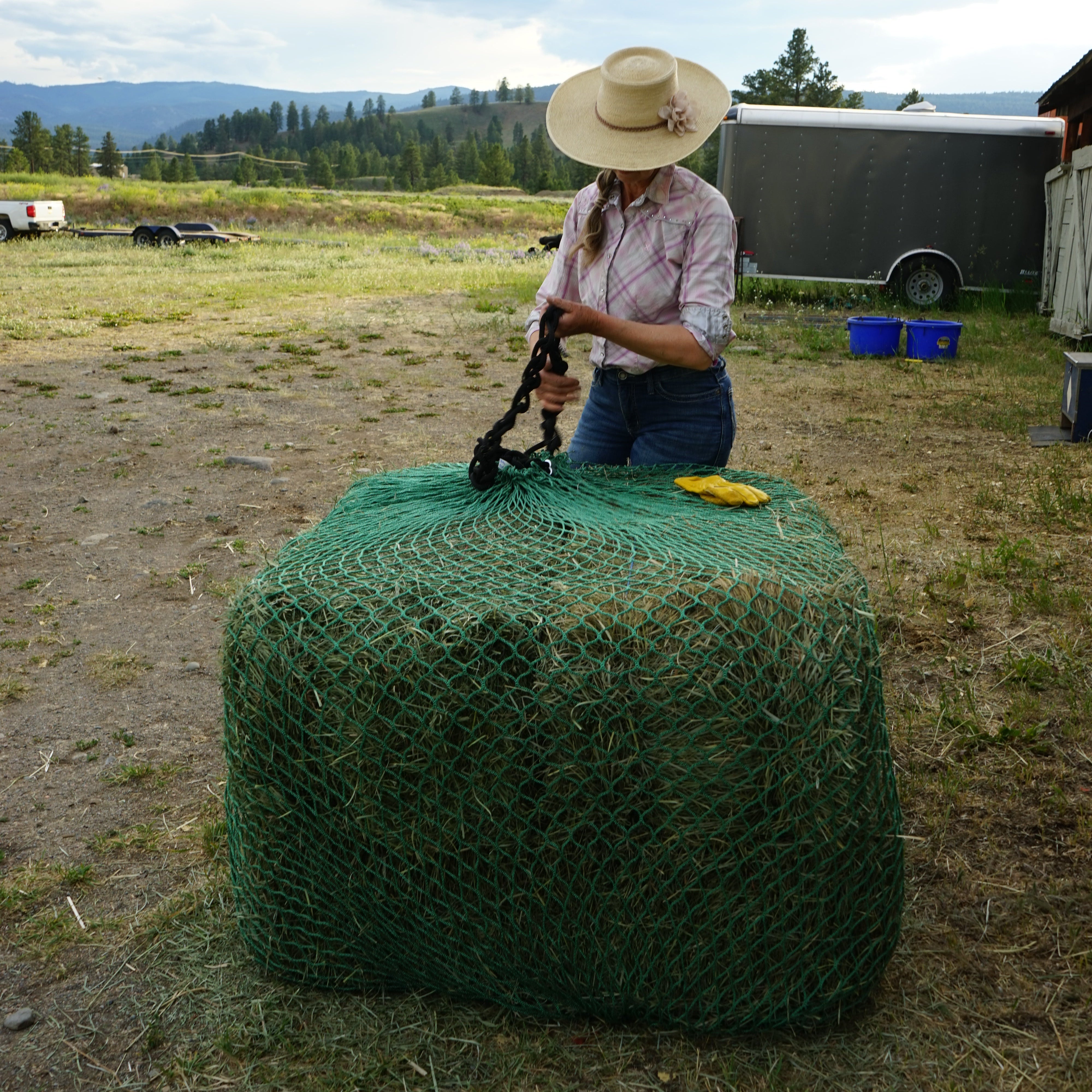 women tying bale slip with green hay netting