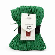 Green hay net wrapped up with braided black rope white paper hangtag reading 'DAY bag' and 'HOLDS - 8 HAY FLAKES', photographed on a clean white background.
