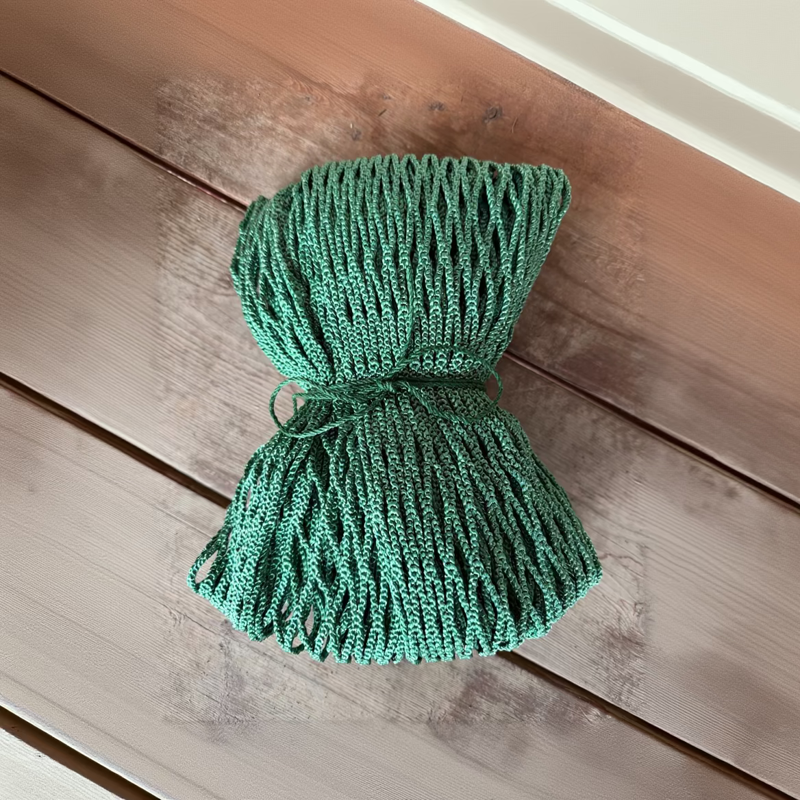 Green rope tied into a bundle on a wooden surface