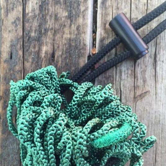 A black toggle, also known as a cord lock, attached to a green hay net