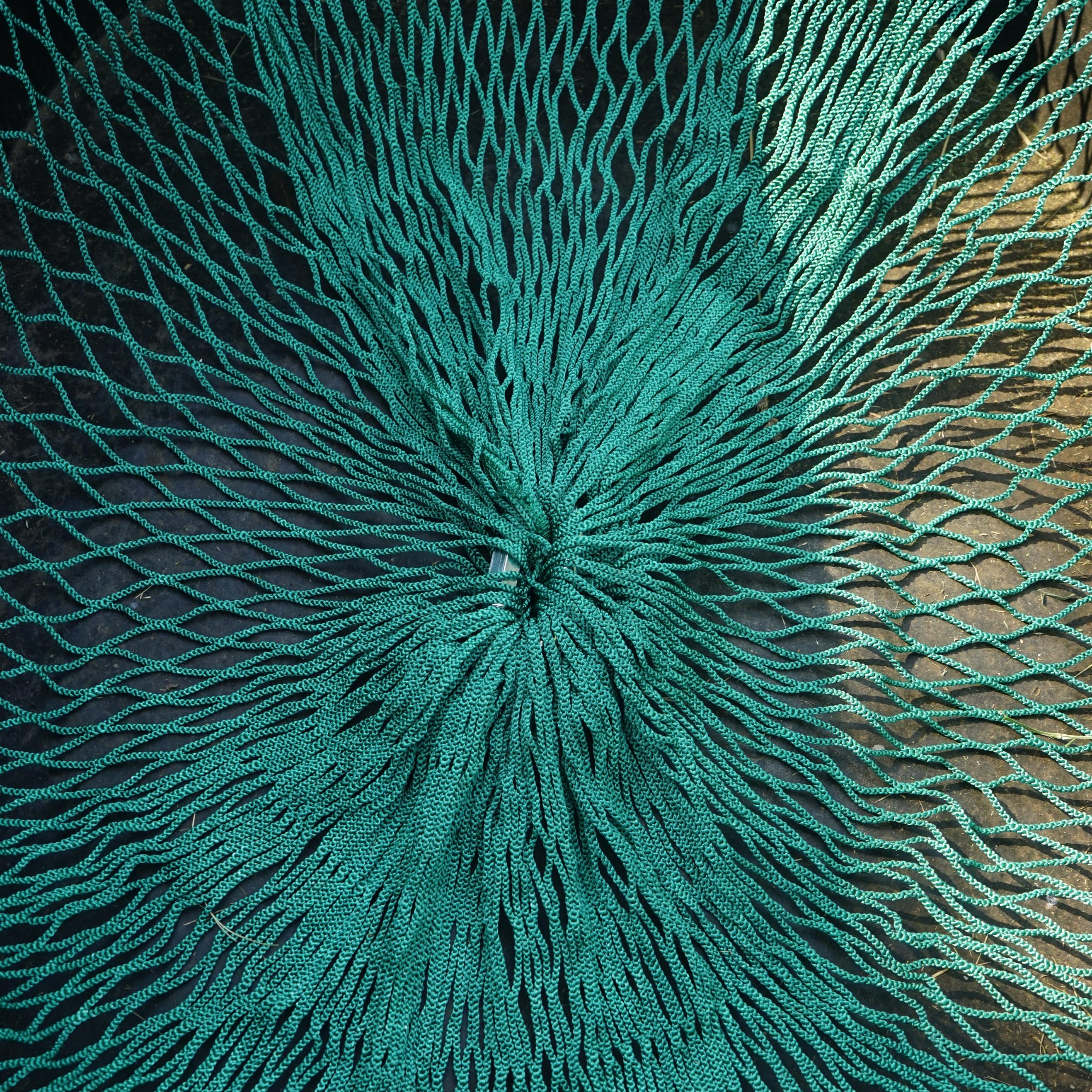 Close-up of a textured teal fabric with a starburst pattern on a black background